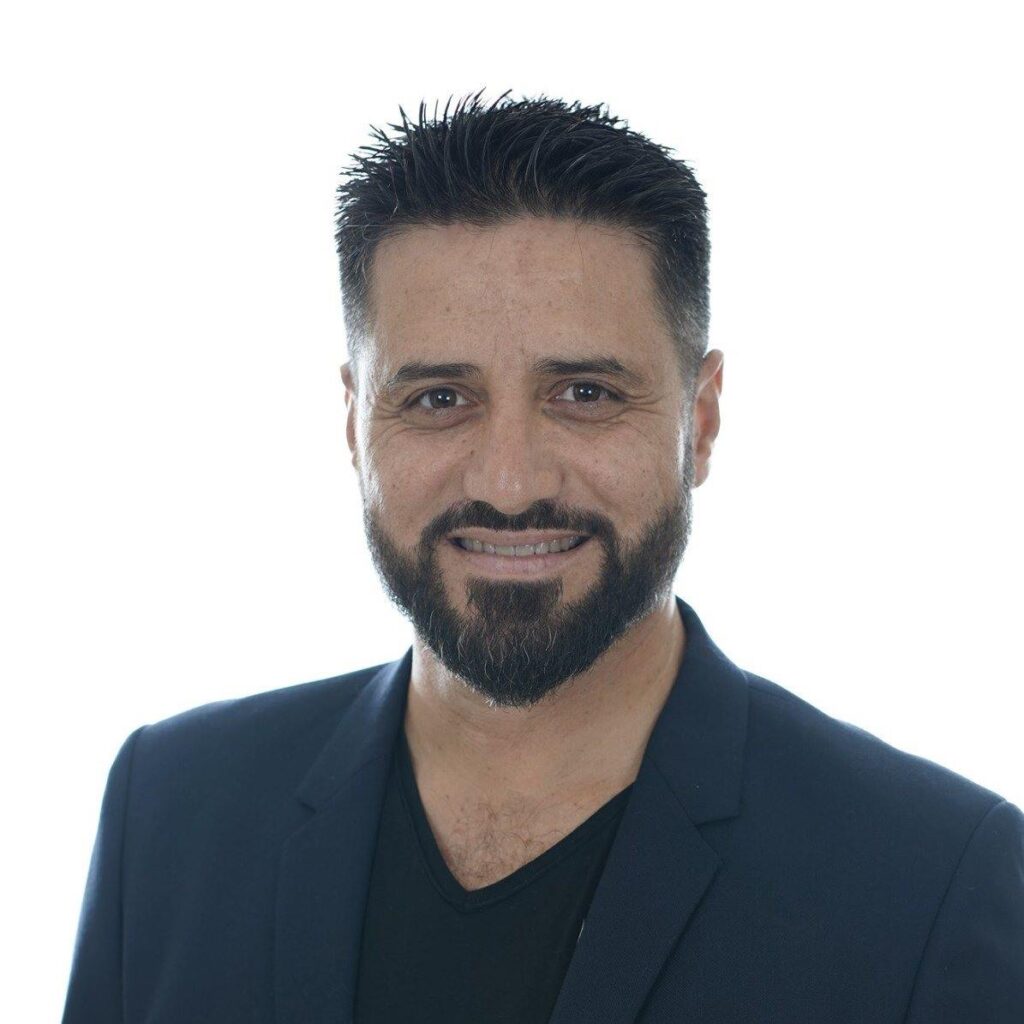 גבר עם זקן מחייך למצלמה.